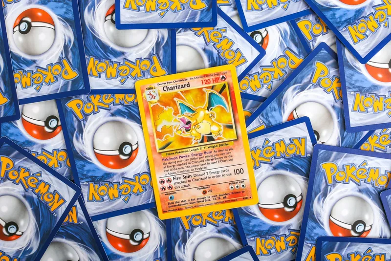 A dense carpet of Pokemon cards lying face down showing their blue Pokeball backs, with one Base Set Charizard lying face up in the middle