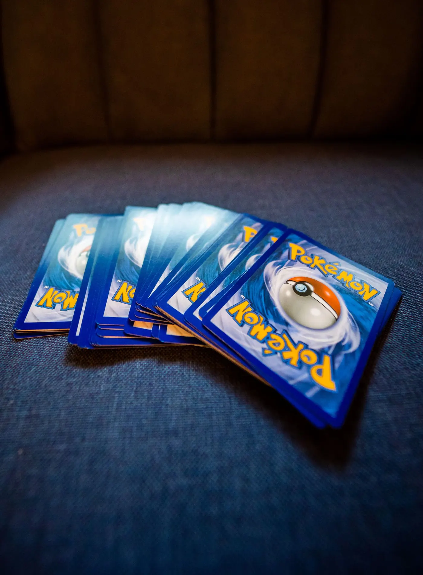 A fanned pile of Pokemon card backs resting on a blue couch